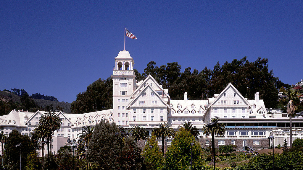 A white building with a flag on top with Claremont Hotel & Spa in the background.